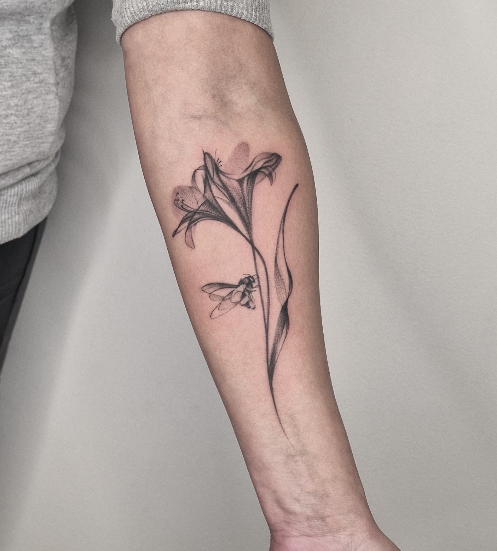 Flowers and bumblebee tattoo on the forearm
