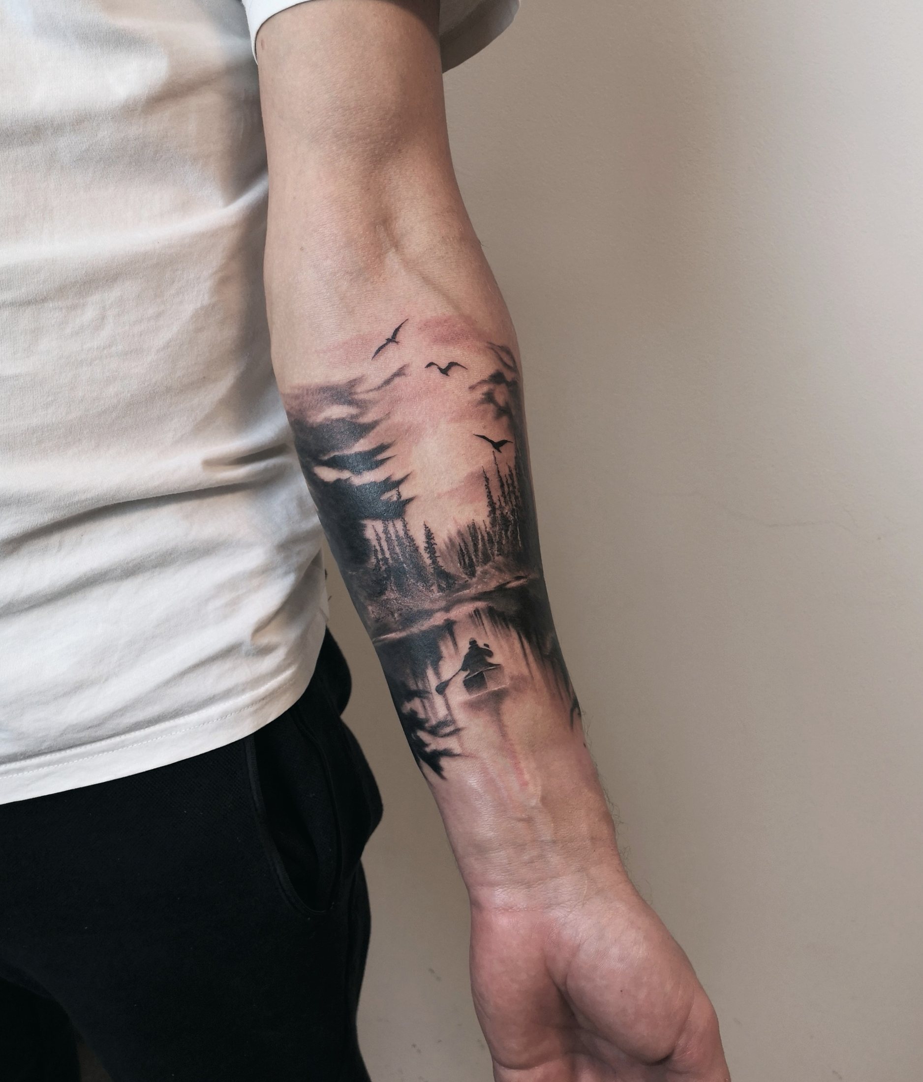 Forest and boating landscape tattoo on the forearm