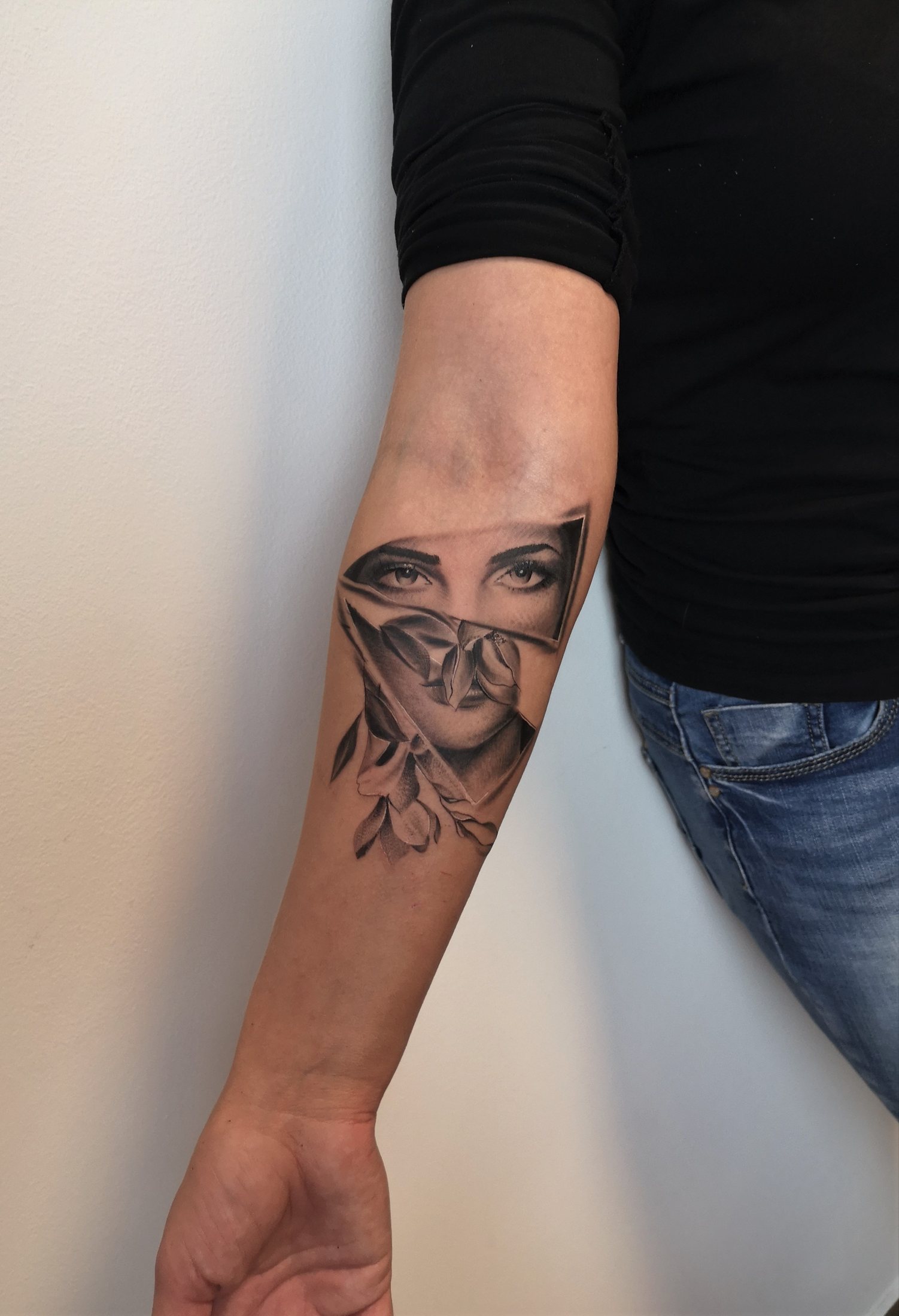 Tattoo of a woman's portrait and flowers on the forearm